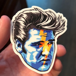 May include: A sticker of a man's face with a blue, white, and yellow lightning bolt design.
