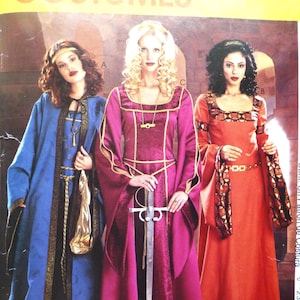 May include: Image of a costume pattern featuring three medieval-style dresses. The dresses are in blue, magenta, and orange, with gold trim and long sleeves. The pattern is labeled "McCall's Costumes".
