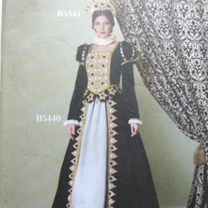 May include: A Butterick sewing pattern for a historical costume, featuring a woman in a black and gold gown with a white underskirt. The dress has red and gold embellishments and a matching headpiece. The pattern number is B5440.
