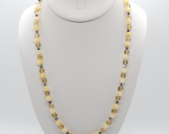 May include: A long necklace made of alternating yellow and gray beads. The necklace is on a white mannequin.