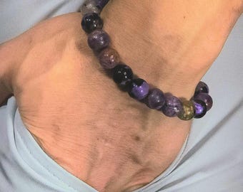 May include: A purple and brown beaded bracelet with a variety of shades of purple and brown beads.