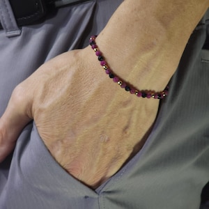 May include: A bracelet with pink and black beads and gold accents.