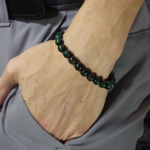 Puede incluir: Un brazalete de piedras preciosas verdes con cuentas verde oscuro y verde claro.