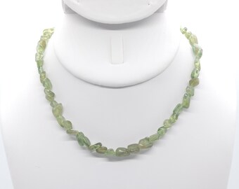 May include: A green gemstone necklace made of irregular shaped stones. The necklace is displayed on a white mannequin bust.