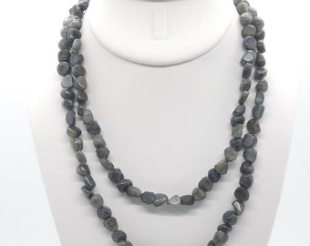 May include: A layered necklace featuring smooth, irregular-shaped beads in shades of gray and blue. The necklace is displayed on a white mannequin, showcasing its draped design and natural stone appearance. The beads vary in size and shape.