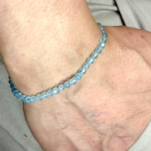 May include: A light blue beaded bracelet on a person's wrist.