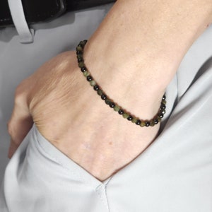 May include: A black and green beaded bracelet with small round beads.