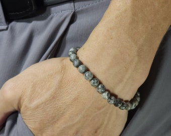 May include: A gray and black beaded bracelet with a simple design.