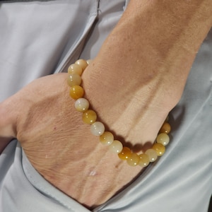 May include: A bracelet made of round, light brown and yellow beads.