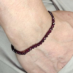 May include: A dark purple gemstone bracelet with small, faceted beads.