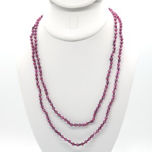 May include: A double strand necklace made of pink gemstone beads on a black cord.