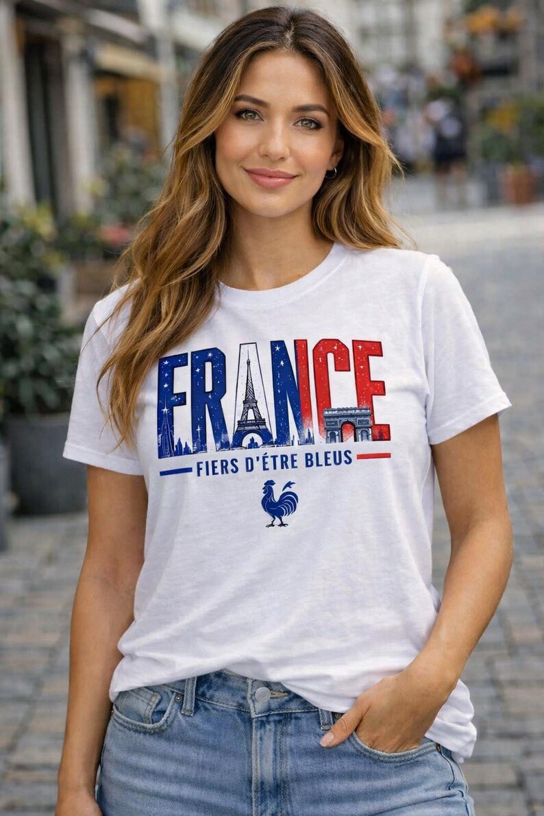 May include: White t-shirt with the word "FRANCE" in blue and red, featuring the Eiffel Tower and Arc de Triomphe. Below the text is "FIERS D'&Ecirc;TRE BLEUS" and a blue rooster graphic. The shirt is worn with blue jeans.