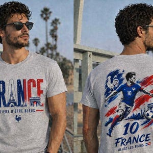 May include: Gray t-shirt with "FRANCE" in blue and red, Eiffel Tower graphic, and "FIERS D'&Ecirc;TRE BLEUS" text. The back features a soccer player in blue, the number 10, and "FRANCE" with "ALLEZ LES BLEUS" text. A rooster and soccer ball are also visible.