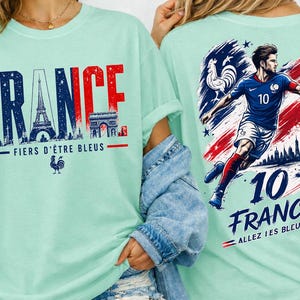 May include: A light green t-shirt with the word "FRANCE" in blue and red, featuring the Eiffel Tower and Arc de Triomphe. The back of the shirt has a soccer player and the text "10 FRANCE".