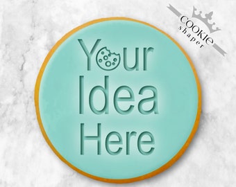 May include: A light blue cookie cutter with a gold outline. The cutter is shaped like a circle and has the text "Your Idea Here" engraved on it.