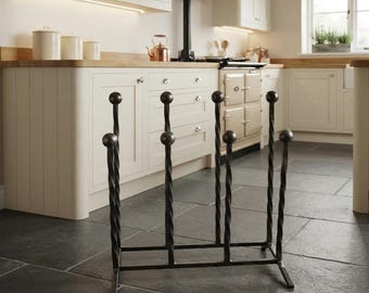 May include: A black metal boot rack featuring a rectangular base with four vertical, twisted metal rods. Each rod is topped with a spherical finial, designed to hold footwear in an inverted position for storage and drying in a kitchen setting.
