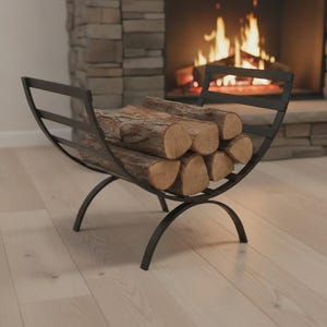 May include: A black metal log holder with a curved, cradle-like design featuring horizontal slats on the sides. The stand is filled with several stacked, cylindrical brown wooden logs, showcasing their textured bark and light-coloured wood grain ends.