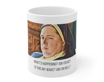 May include: White ceramic coffee mug with a colorful image of a woman wearing a black and white habit. The text on the mug reads "WHAT'S HAPPENING? AM I DEAD? IS THIS MY WAKE? AM I IN HELL?"