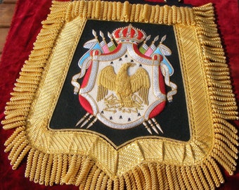 May include: A gold embroidered heraldic banner with a crown, eagle, and spears. The banner is trimmed with gold fringe and has three rings at the top.