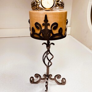 May include: A gold and silver watch with a white face is displayed on a decorative stand with a wooden base and black metal accents.