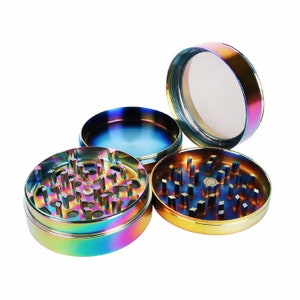 May include: A four-piece metal grinder with a rainbow iridescent finish. The grinder has a top lid, a chamber with teeth, a screen, and a collection chamber.