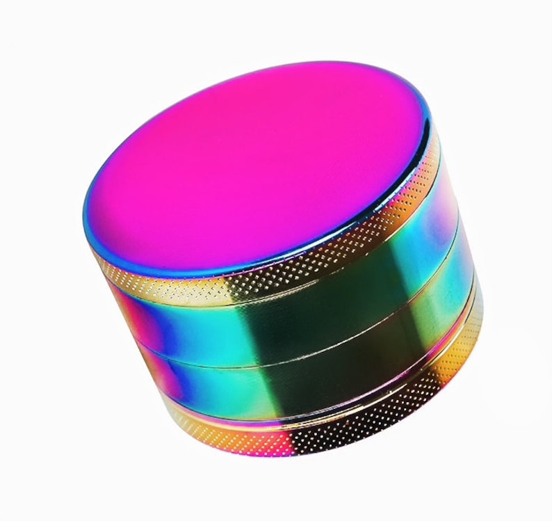 May include: A multi-colored metal grinder with a pink top and a rainbow finish.