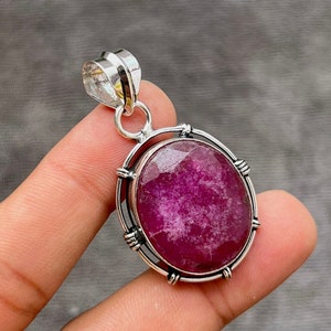 Puede incluir: Un colgante de plata con una piedra preciosa grande, ovalada y rosa engastada en un bisel de plata. El colgante tiene una argolla de plata.