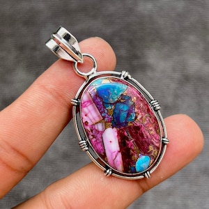 May include: A silver pendant with a large oval-shaped stone. The stone is a mix of pink, purple, and blue colors with a swirling pattern.