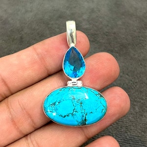 May include: A silver pendant with a turquoise oval stone and a teardrop-shaped blue topaz.