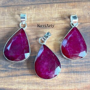 May include: Three teardrop-shaped pendants featuring faceted deep magenta gemstones set in silver-toned metal bails. Each pendant displays a unique crystalline texture and vibrant pinkish-red hue. The text KaviArty is visible in the center.