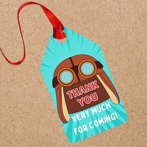 May include: A blue tag with a brown aviator helmet graphic and the words "THANK YOU VERY MUCH FOR COMING!" in white and red. The tag has a red ribbon attached at the top.