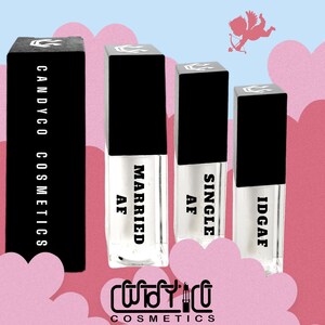 Puede incluir: Tres tubos de brillo labial transparentes con tapas negras y etiquetas blancas. Las etiquetas dicen "Married AF", "Single AF" y "IDGAF". Los tubos están dispuestos de izquierda a derecha en orden de las etiquetas. El fondo es rosa con nubes blancas y un pequeño Cupido con una flecha.