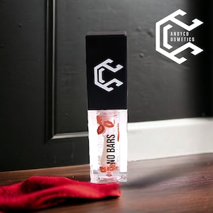 Puede incluir: Un tubo transparente de brillo de labios con labios rojos en su interior. El tubo está etiquetado con "NO BARS" y tiene una tapa negra con un logotipo blanco. El logotipo es una letra "C" estilizada dentro de un hexágono.