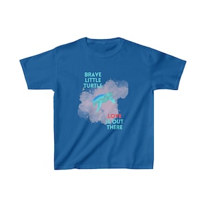 Op de afbeelding: Een blauw jeugd T-shirt met een aquarel ontwerp van een zeeschildpad die zwemt met de tekst "Brave Little Turtle" en "Love is Out There" in roze en blauw.