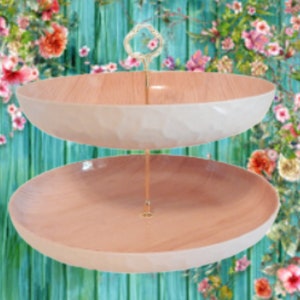 May include: Two-tiered serving stand with a wooden base and white rim. The stand has a gold metal rod connecting the two tiers.