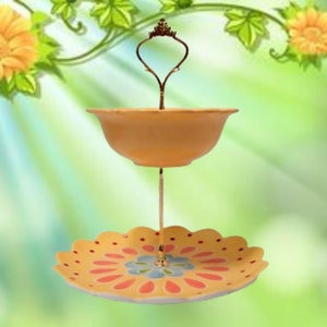 Op de afbeelding: Een twee-traps serveerstandaard met een geel en oranje bloemenontwerp. De bovenste laag is een kom en de onderste laag is een bord. De standaard heeft een gouden metalen handvat.