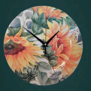 Könnte beinhalten: Runde Wanduhr mit einem Sonnenblumenmuster in Gelb und Orange, grünen Blättern und schwarzen Zeigern. Die Uhr befindet sich vor einem dunkelgrünen Hintergrund mit goldenem Rand, ein dekoratives Element.