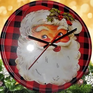 May include: A red and black buffalo plaid clock with a vintage Santa Claus face in the center. The clock hands are black and gold.