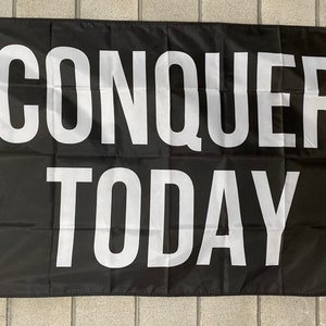 May include: Black flag with white text that reads "CONQUER TODAY".