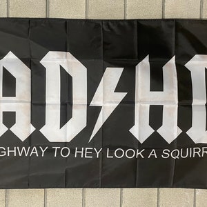 Könnte beinhalten: Schwarze Flagge mit weißem Text, der "ADHD" mit einem Blitz zwischen dem "D" und dem "H" lautet. Unter dem Text steht "HIGHWAY TO HEY LOOK A SQUIRREL"