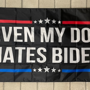 May include: Black flag with white text that reads "EVEN MY DOG HATES BIDEN". The flag has a red stripe with five white stars at the top and a blue stripe with five white stars at the bottom.