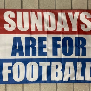 Pode incluir: Uma bandeira vermelha, branca e azul com o texto "Sundays Are For Football" impresso nela.