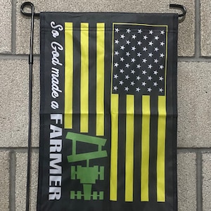 May include: A black garden flag with a yellow and black American flag design. The flag has a green tractor silhouette and the text "So God made a FARMER".