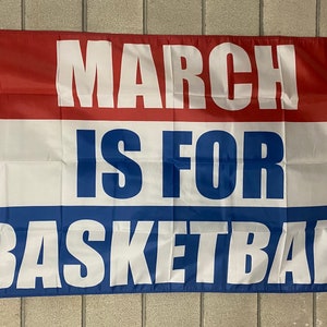 Può includere: Una bandiera rosso, bianco e blu con il testo "MARCH IS FOR BASKETBALL" stampato in lettere bianche e blu.