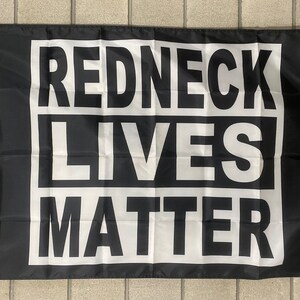 Könnte beinhalten: Schwarz-weiße Flagge mit dem Text "REDNECK LIVES MATTER" in fetten weißen Buchstaben auf schwarzem Hintergrund.