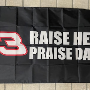 May include: A black flag with a white number "3" with a red outline. The text "RAISE HELL PRAISE DALE" is printed in white on the flag.