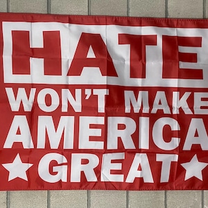 May include: Red flag with white text that reads "Hate Won't Make America Great" with a white star on each side of the text.