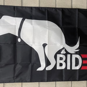 May include: A black flag featuring a white silhouette of a dog defecating. The dog is wearing a collar and has a tail. The text "BIDEN" is written in white letters below the dog, with three red stripes underneath.