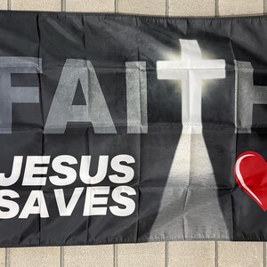 May include: Black flag with the word "FAITH" in large white letters at the top, and "JESUS SAVES" in white below. A white cross is centered, with a red heart on the lower right.