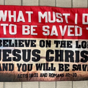 May include: A rectangular red and white flag with the text "WHAT MUST I DO TO BE SAVED?" in white. Below, it reads "BELIEVE ON THE LORD JESUS CHRIST AND YOU WILL BE SAVED" with Acts 16:31 and Romans 10:-10 at the bottom.